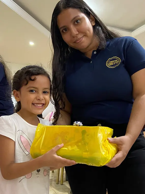 Niña recibiendo un obsequio de una voluntaria