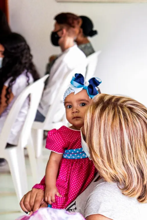 Bebé con vestido rosa en brazos de su mamá